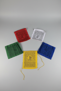 Five Tibetan prayer flags in red, white, green, yellow and blue fanned out, grey studio background
